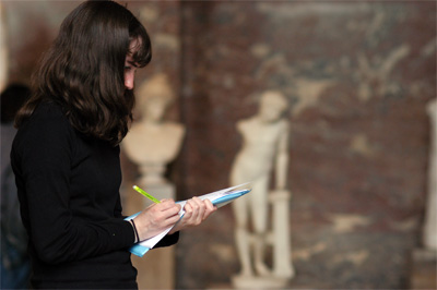 Jeune femme prenant des notes devant une statue d'Athena Jeune femme prenant des notes devant une statue d'Athena